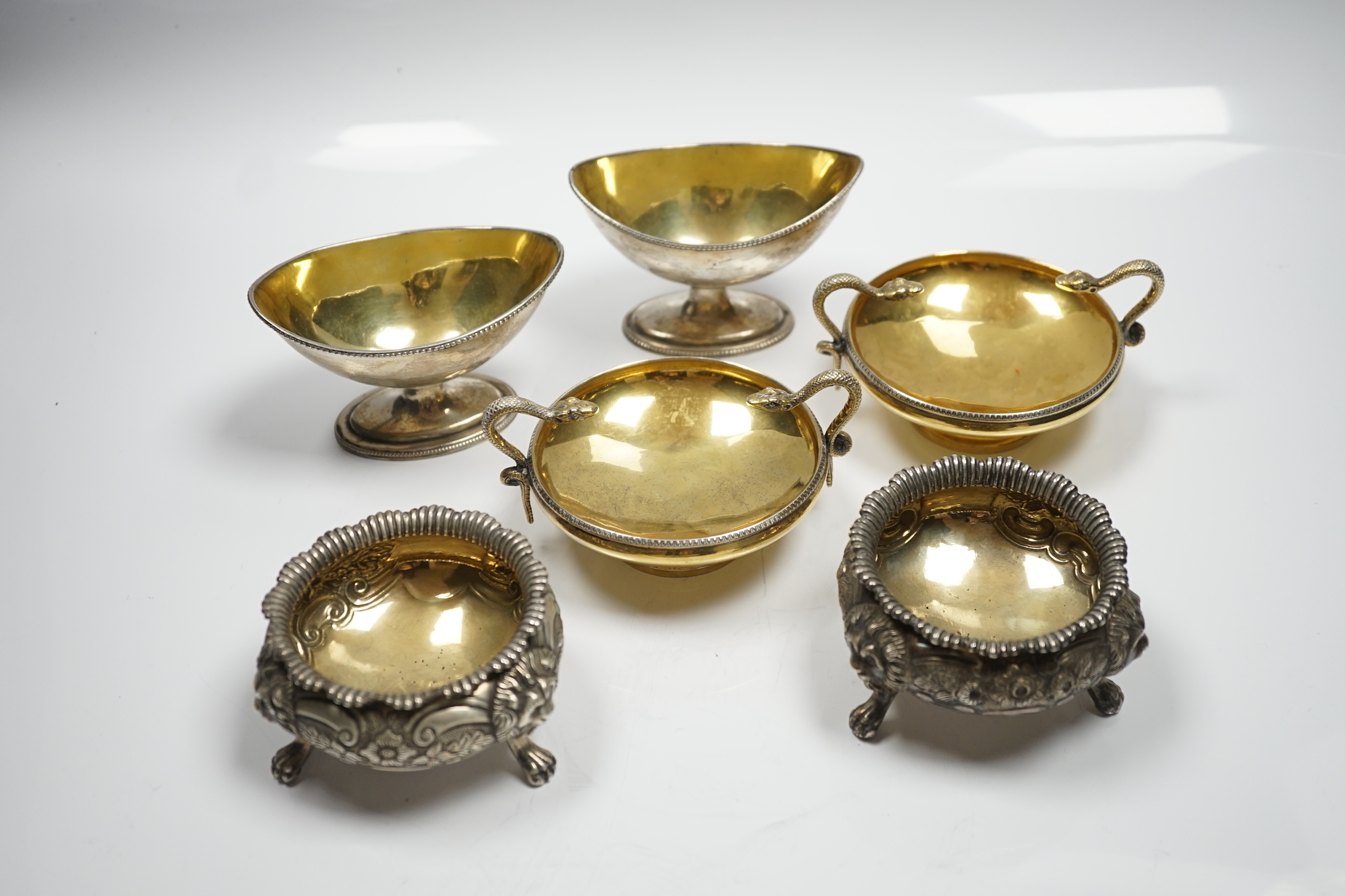 A pair of George V silver gilt shallow pedestal salts, with twin serpent handles, William Hutton & Sons, Ltd, Sheffield, 1928, width 11.8cm over handles, together with two matched pairs of Georgian silver salts, 20.3oz.